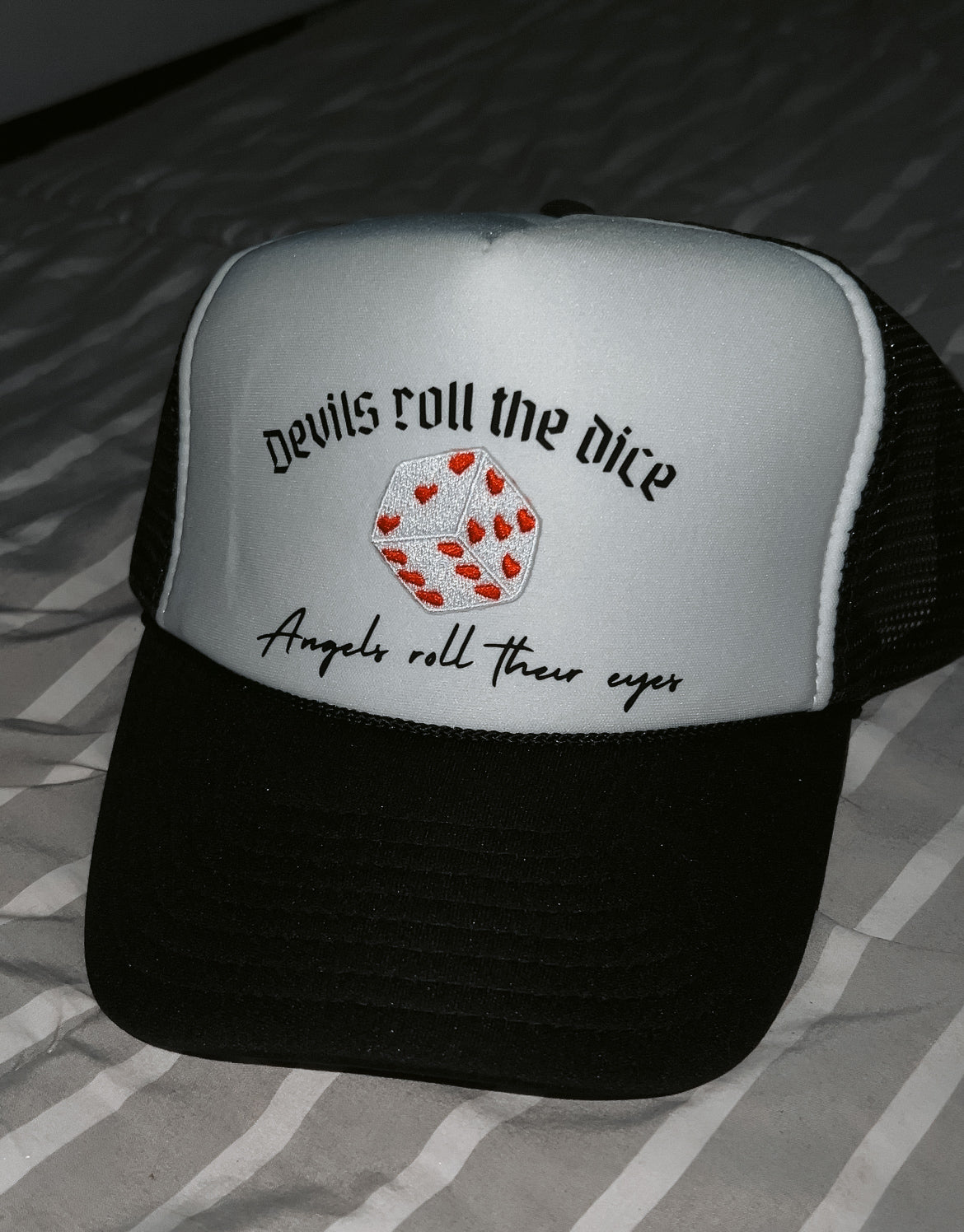 black and white hat with "devils roll the dice, angels roll their eyes" quote and dice patch